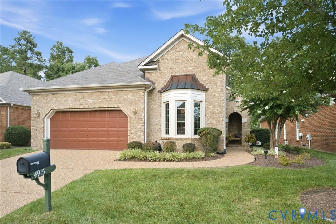 Brick facade with a large bay window, an arched entry, an attached garage, and a curved walkway