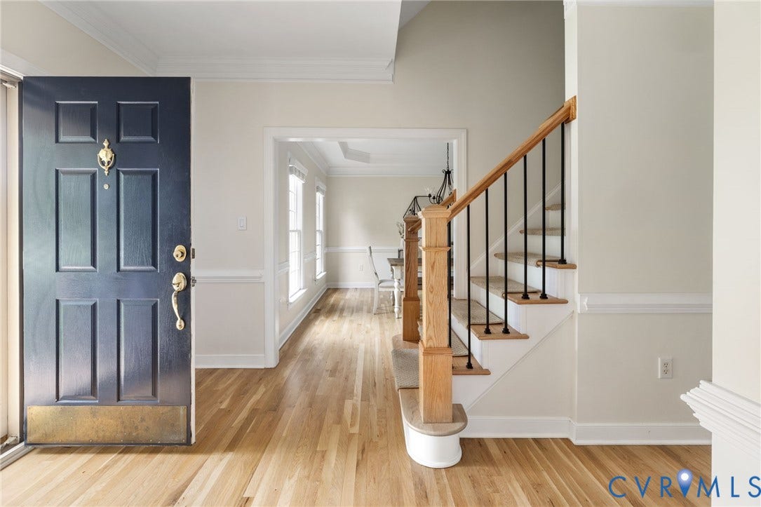12305 Bradford Landing Way, Wyndham, Glen Allen, VA 23059 Entryway featuring a paneled front door, oak hardwood flooring, a staircase with wood newel posts and balustrade, and a formal dining area with multiple windows
