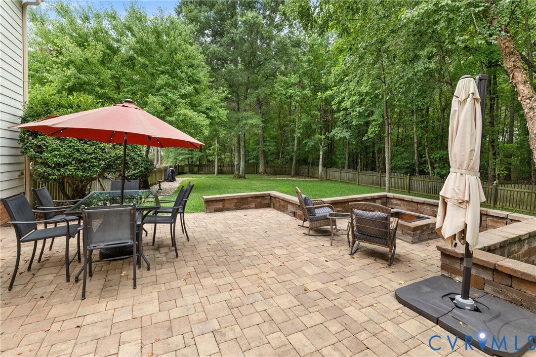 12305 Bradford Landing Way, Wyndham, Glen Allen, VA 23059 Expansive paver patio featuring a built-in fire pit, stone retaining walls, and a manicured lawn surrounded by mature trees