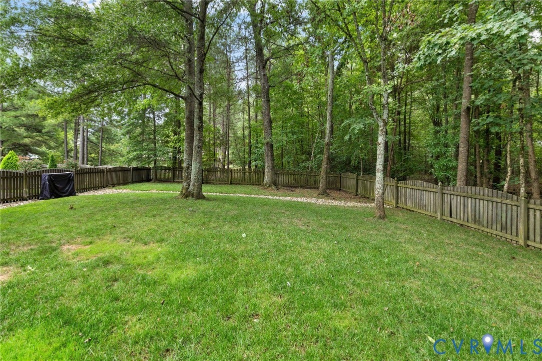12305 Bradford Landing Way, Wyndham, Glen Allen, VA 23059 Fenced backyard featuring a lush lawn, mature trees, and natural wooded surroundings