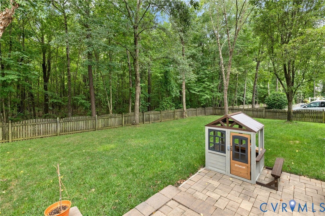 12305 Bradford Landing Way, Wyndham, Glen Allen, VA 23059 Expansive green lawn with a privacy fence bordering a dense natural tree line
