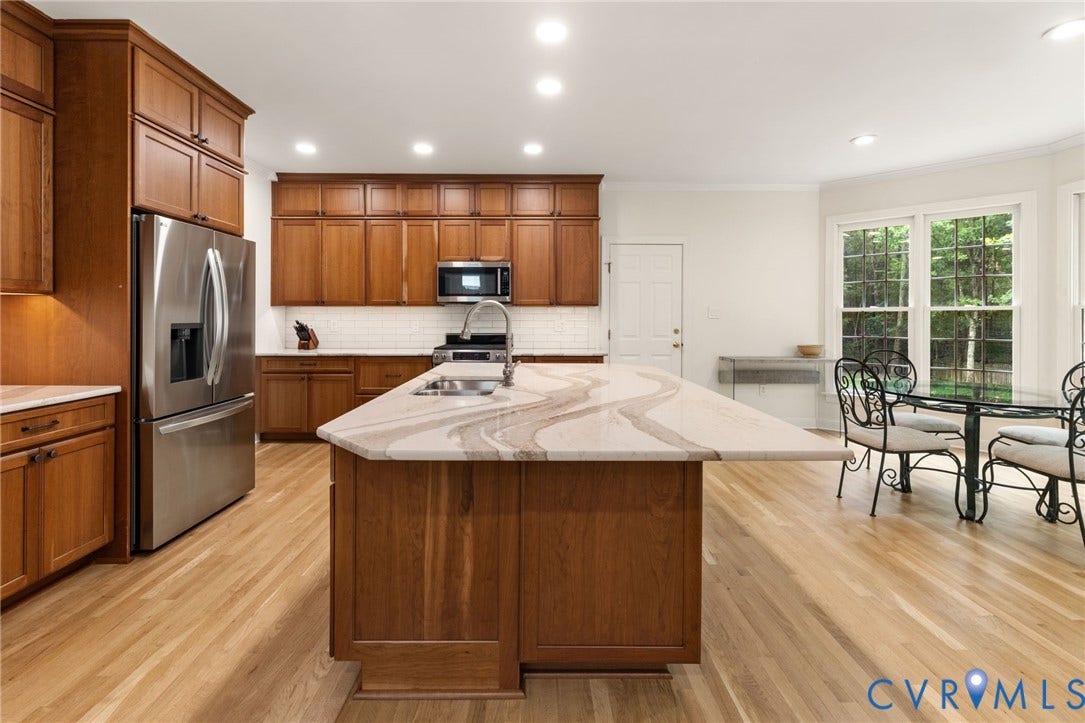 12305 Bradford Landing Way, Wyndham, Glen Allen, VA 23059 Renovated Gourmet kitchen featuring a Quartz countertops oversized island with integrated sink, wood-finish flooring, stainless steel appliances, extensive cabinetry, and a subway tile backsplash