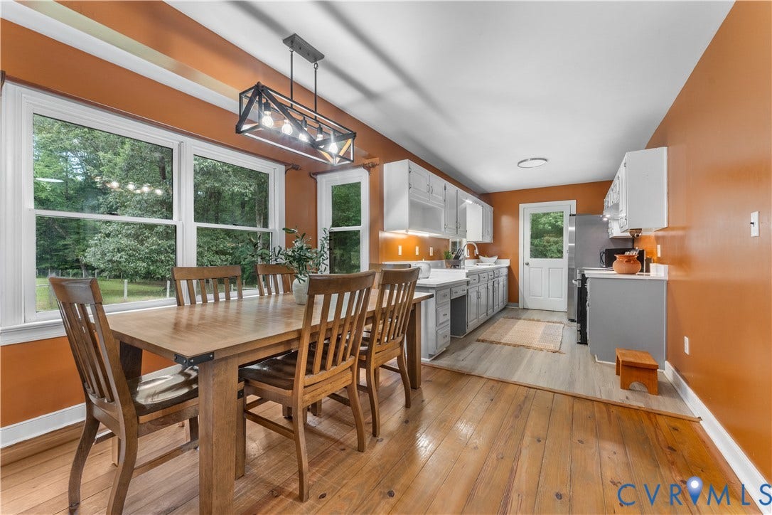 3927 Hughes Creek Road, Powhatan, VA 23139 Expansive windows, wood-finish flooring, white cabinetry, integrated sink, and a modern linear chandelier