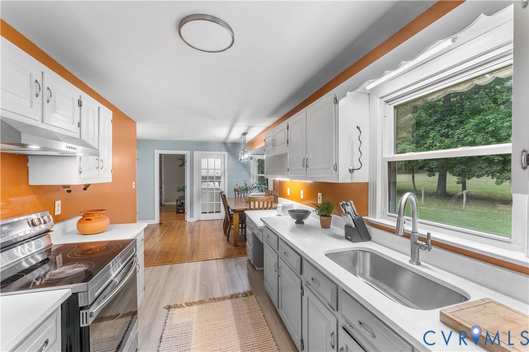 3927 Hughes Creek Road, Powhatan, VA 23139 White cabinetry with stainless steel hardware, white countertops, built-in stainless steel oven, undermount stainless steel sink with gooseneck faucet, and wood-finish flooring