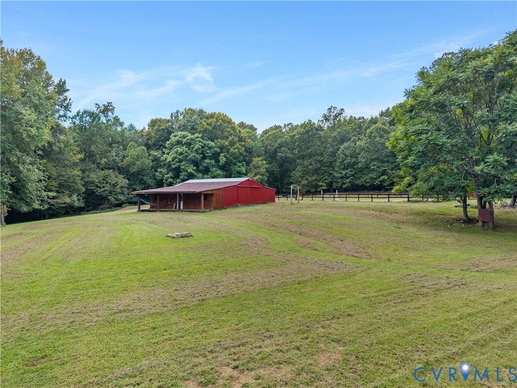 3927 Hughes Creek Road, Powhatan, VA 23139 Expansive green acreage featuring a red barn with a covered porch, perimeter fencing, and mature trees
