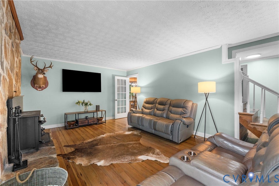 3927 Hughes Creek Road, Powhatan, VA 23139 Hardwood flooring, stone accent wall with hearth, French doors, white trim, and a staircase with wood newel post