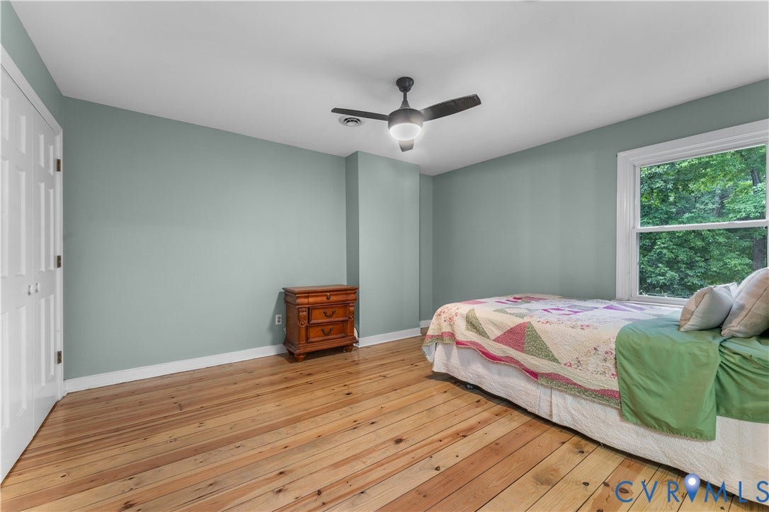 3927 Hughes Creek Road, Powhatan, VA 23139 Hardwood flooring, white paneled bifold doors, window with exterior scenery, ceiling fan with integrated lighting, and light blue wall finish