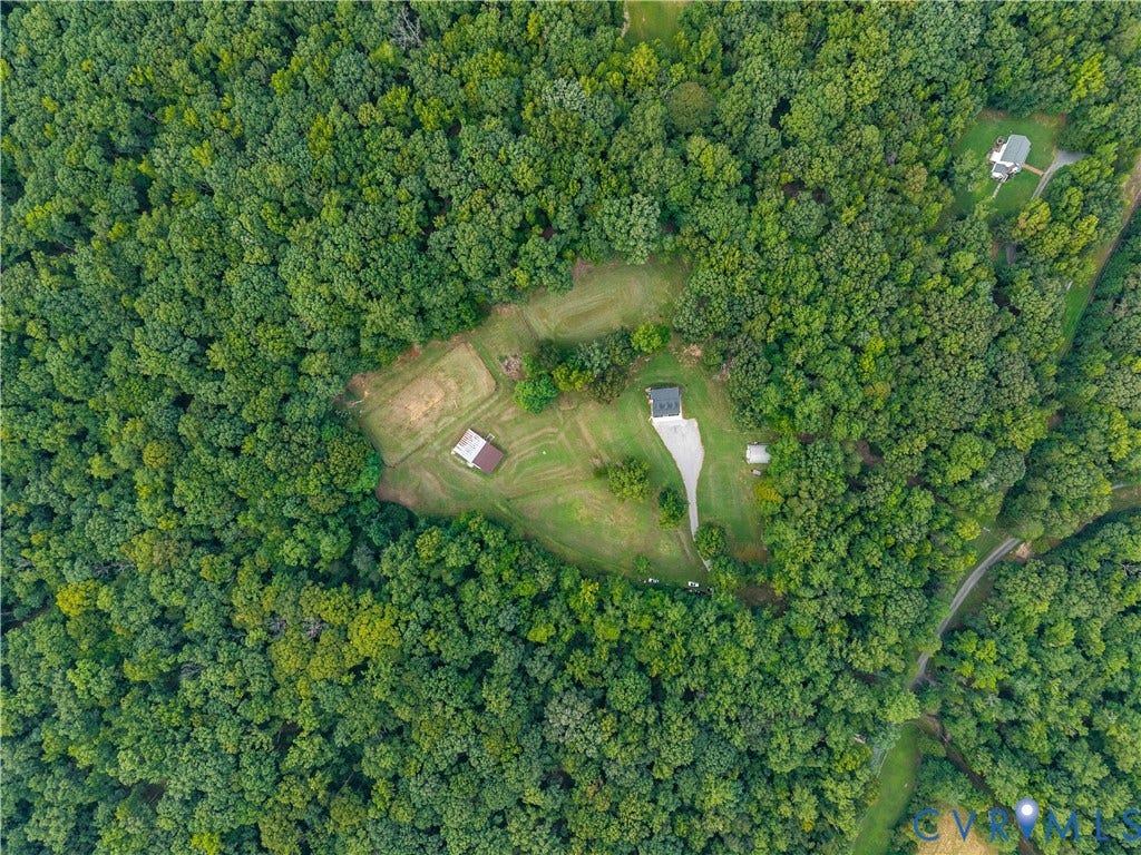 3927 Hughes Creek Road, Powhatan, VA 23139 Expansive wooded acreage featuring a single-story residence, detached outbuilding, cleared lawn areas, and a paved drive
