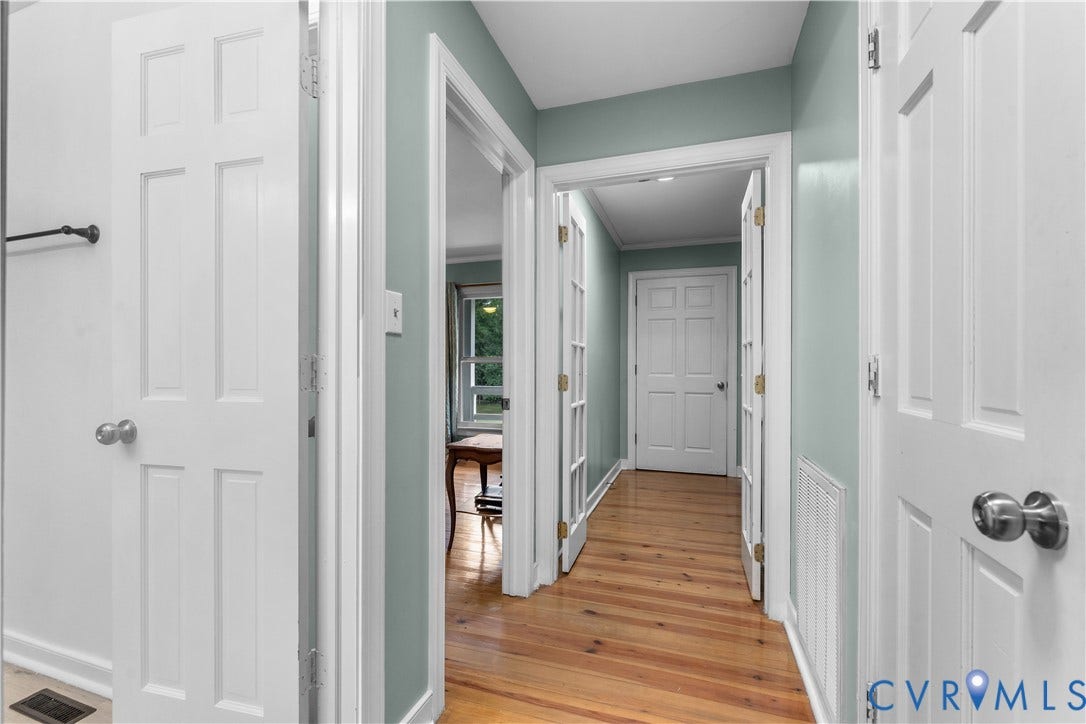 3927 Hughes Creek Road, Powhatan, VA 23139 Hardwood flooring throughout a hallway with white paneled doors and light blue walls
