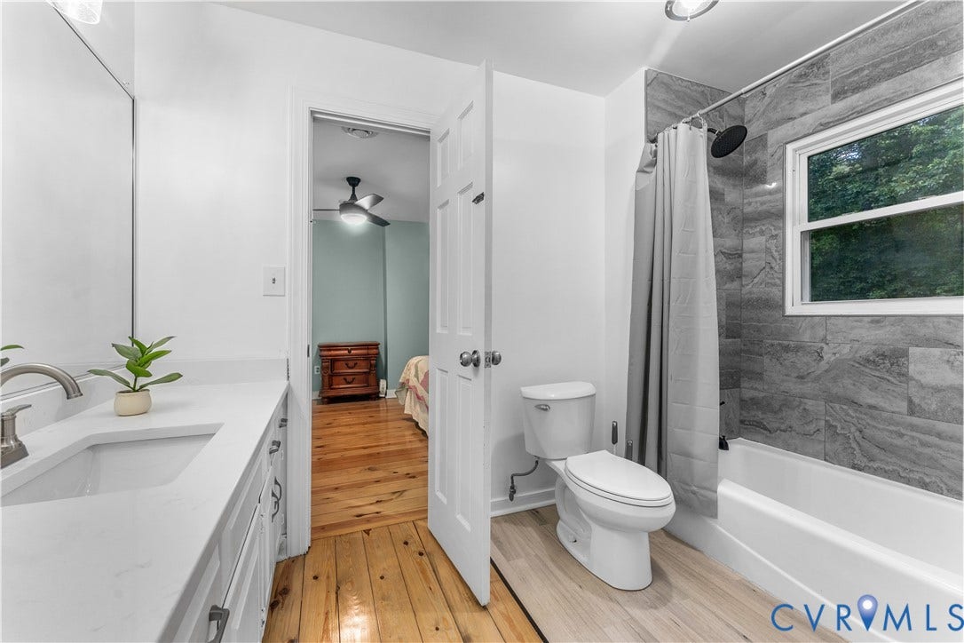 3927 Hughes Creek Road, Powhatan, VA 23139 Bathroom featuring a white vanity with an integrated sink and brushed nickel faucet, a toilet, a shower-tub combination with gray tile surround, and a window