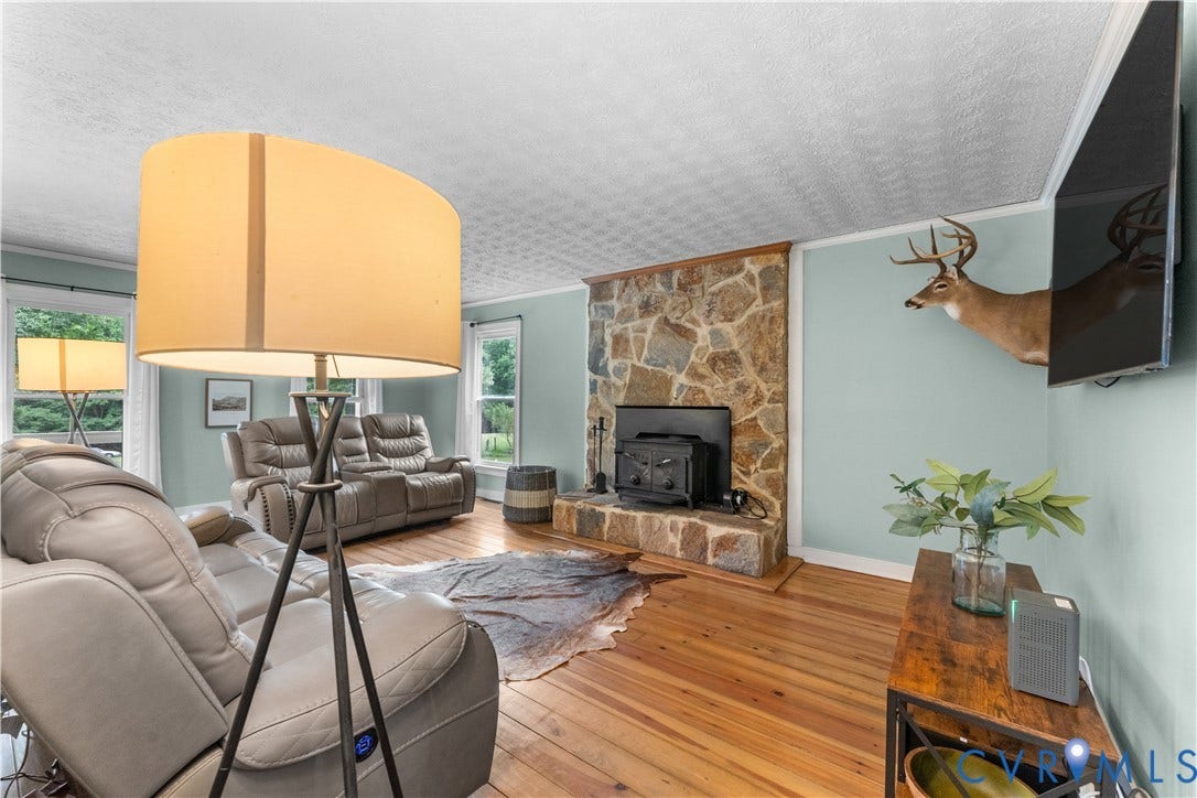 3927 Hughes Creek Road, Powhatan, VA 23139 Stone-clad fireplace with a wood stove insert, rich wood flooring, and light blue walls