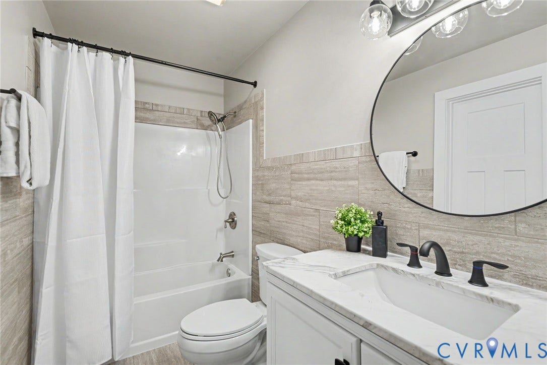 8906 Huntingcreek Place, Chesterfield, VA 23237 White vanity with integrated rectangular sink and dark bronze fixtures, framed round mirror, four-light vanity fixture!