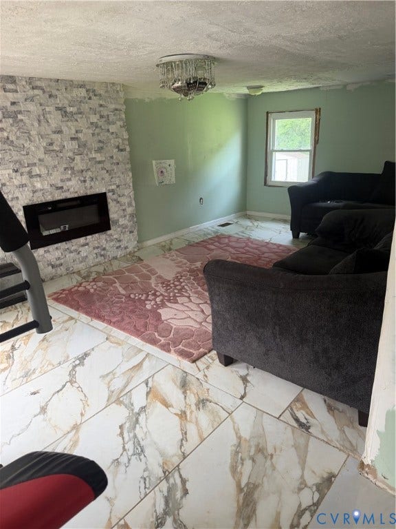 Living area featuring a stone veneer accent wall with an inset fireplace, large format tile flooring, and a crystal chandelier