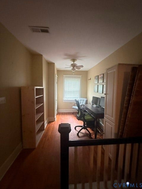 Versatile room featuring wood-finish flooring, a ceiling fan, and built-in cabinetry
