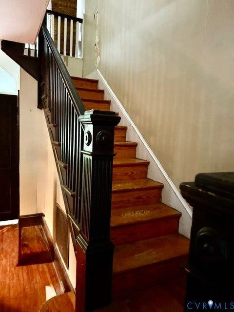 Staircase featuring wood-finish treads and a dark-stained newel post with balusters