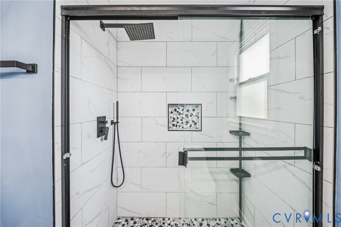 3304 Carlton Road, Henrico, VA 23223 Walk-in shower featuring black-framed glass enclosure, white rectangular wall tiles, and a pebble-finish shower floor