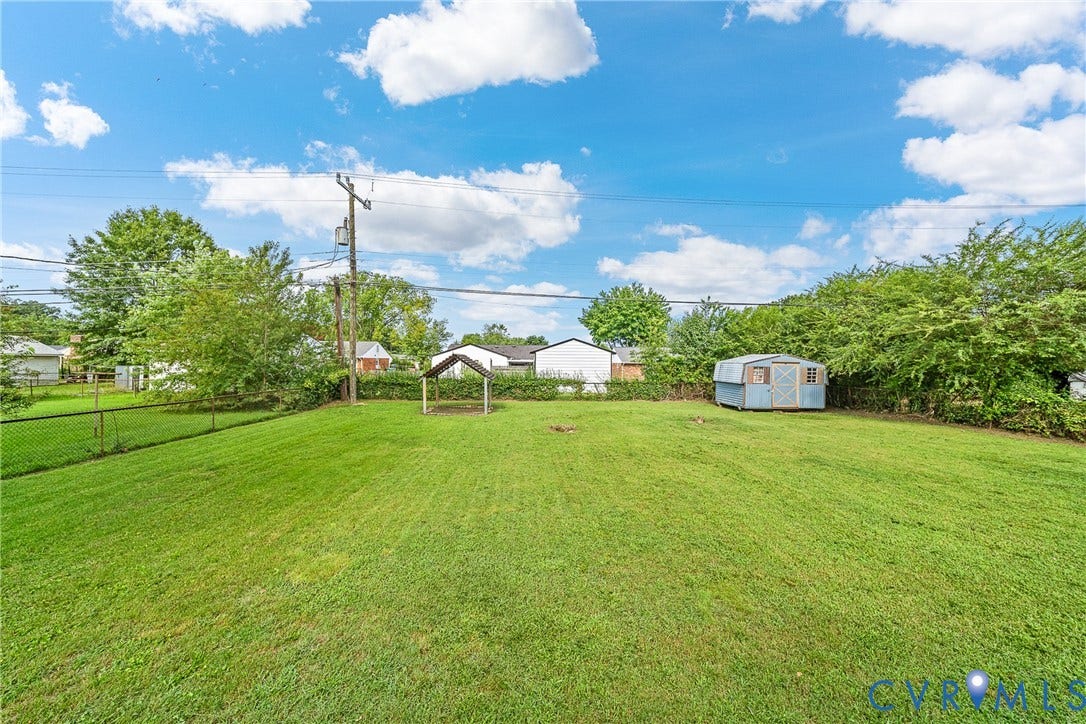 3304 Carlton Road, Henrico, VA 23223 Expansive backyard featuring a lush green lawn, a covered gazebo structure, a blue storage shed, and mature perimeter trees