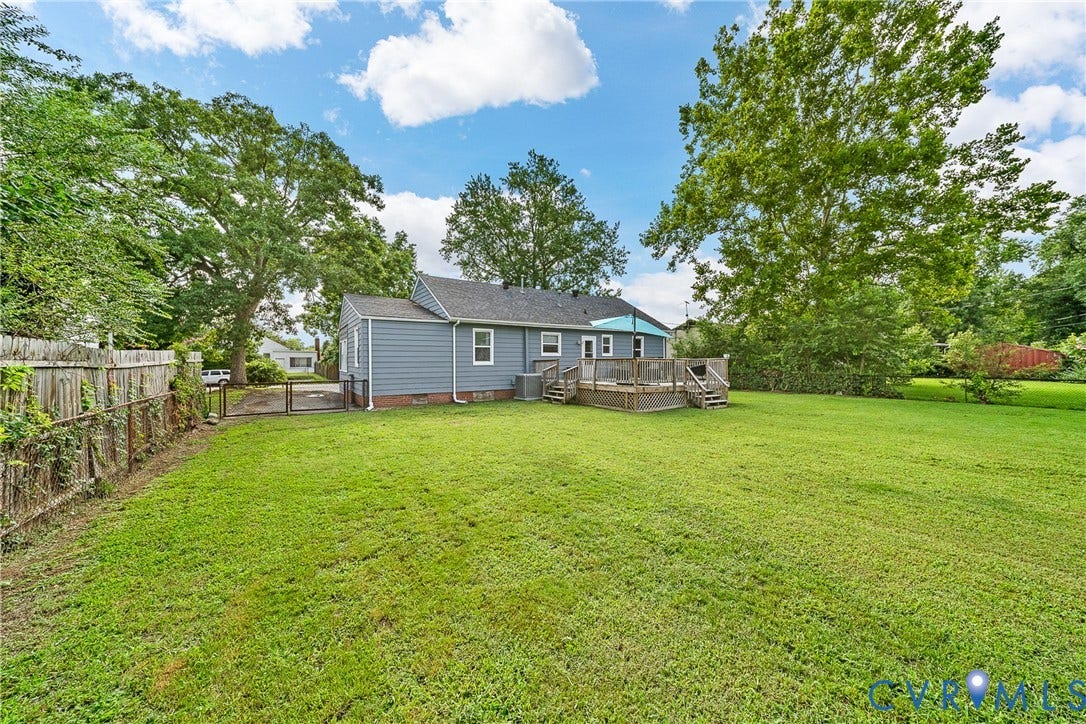 3304 Carlton Road, Henrico, VA 23223 Expansive backyard featuring a manicured lawn, a multi-level wooden deck with stairs, a wooden privacy fence, mature trees, and blue siding on the home's exterior