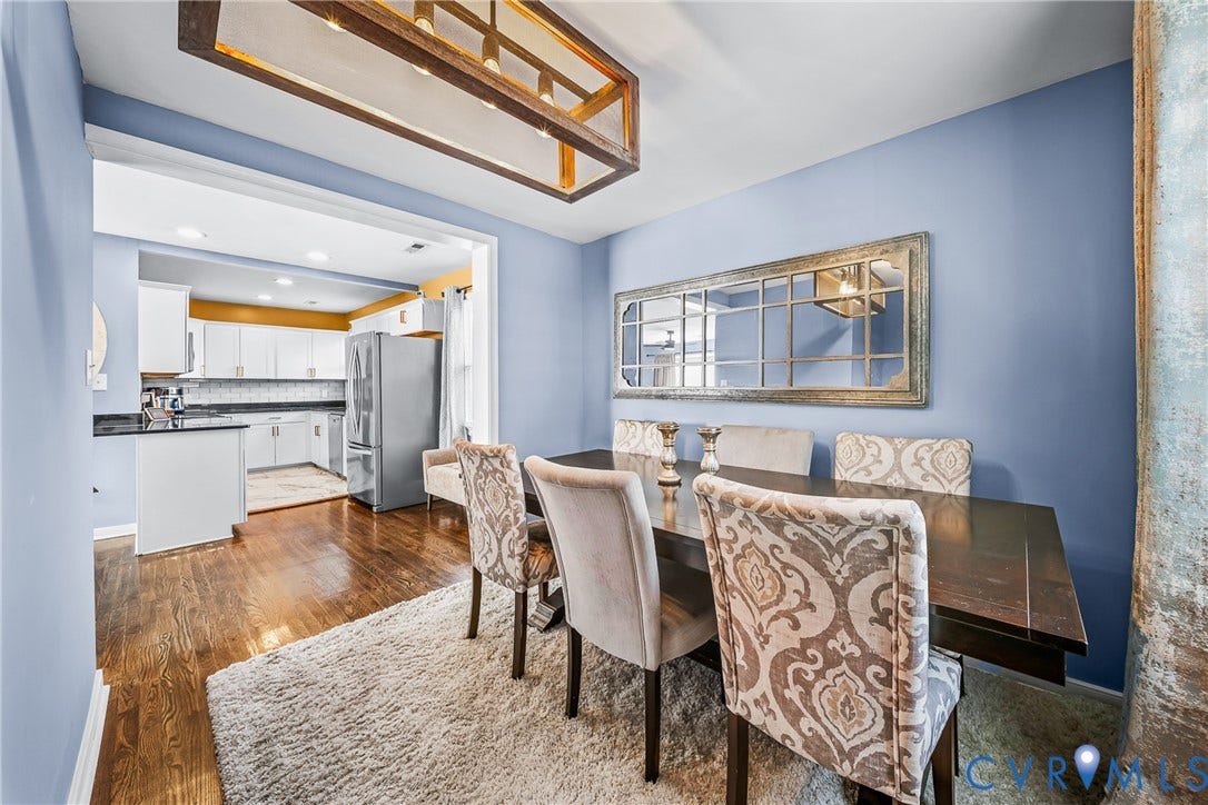 3304 Carlton Road, Henrico, VA 23223 Open concept living space featuring wood-finish flooring, a contemporary wood-frame chandelier, and a spacious kitchen with white cabinetry, stainless steel appliances, and dark countertops