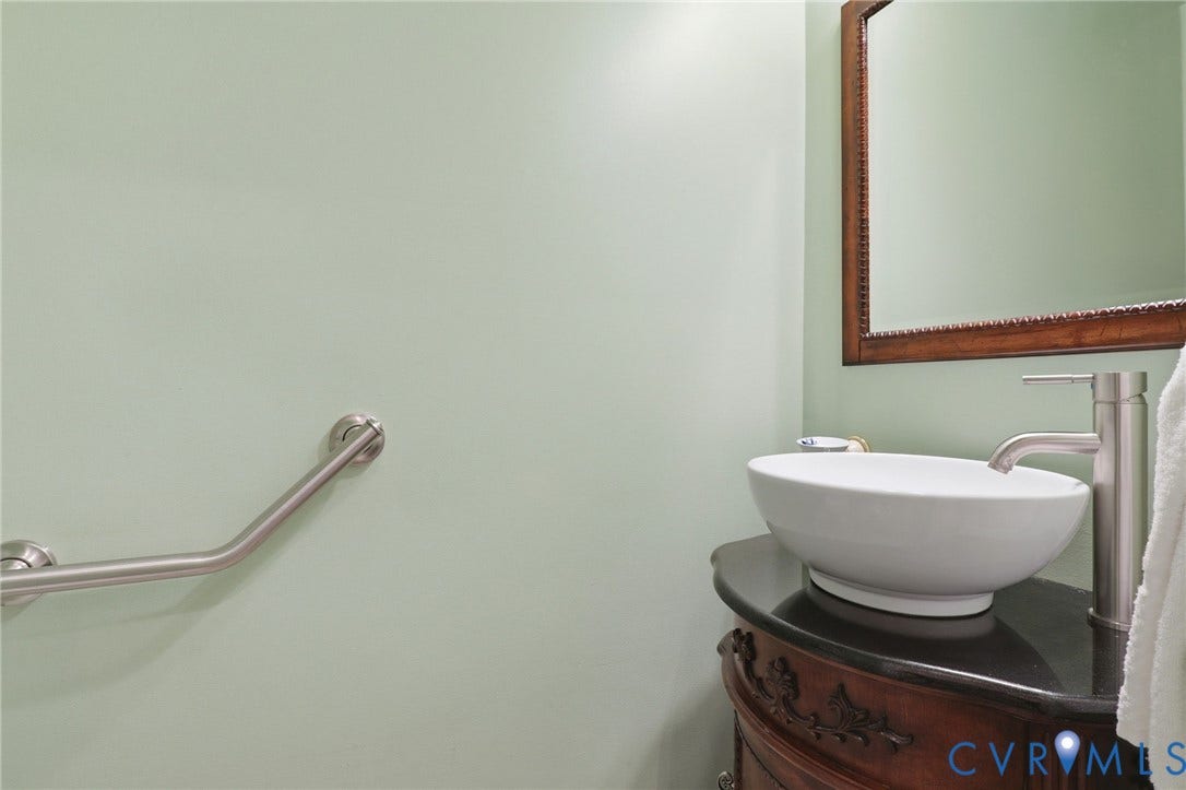 Modern vessel sink with brushed nickel faucet, set upon a dark countertop and ornate wood-finish vanity