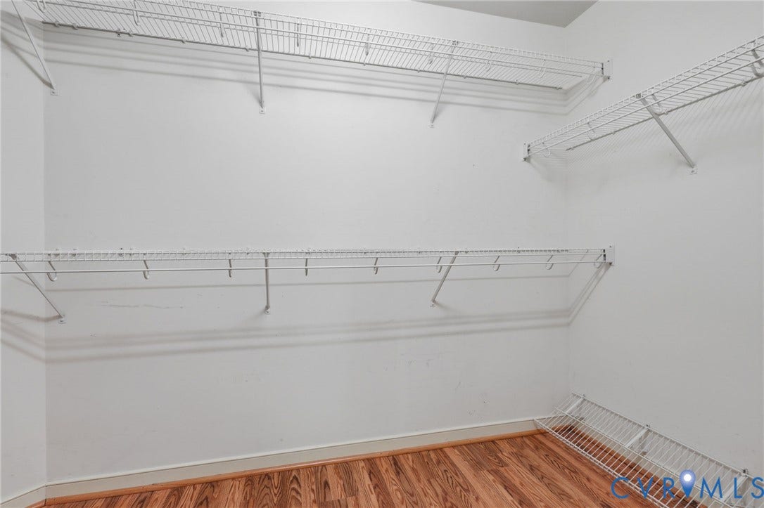 Interior storage space featuring white wire shelving, white walls, and wood-finish flooring