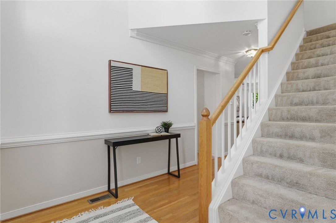 Carpeted staircase with wooden handrail and balusters