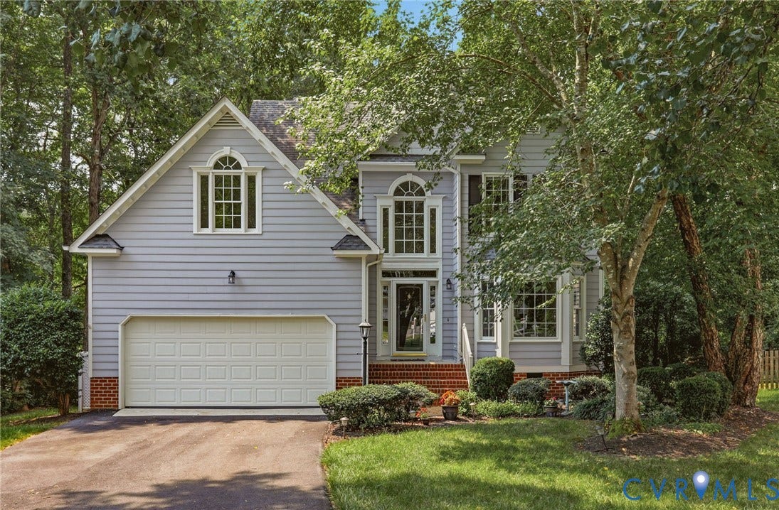 Traditional-style exterior featuring light grey siding with white trim, a prominent two-car garage, and multiple large windows