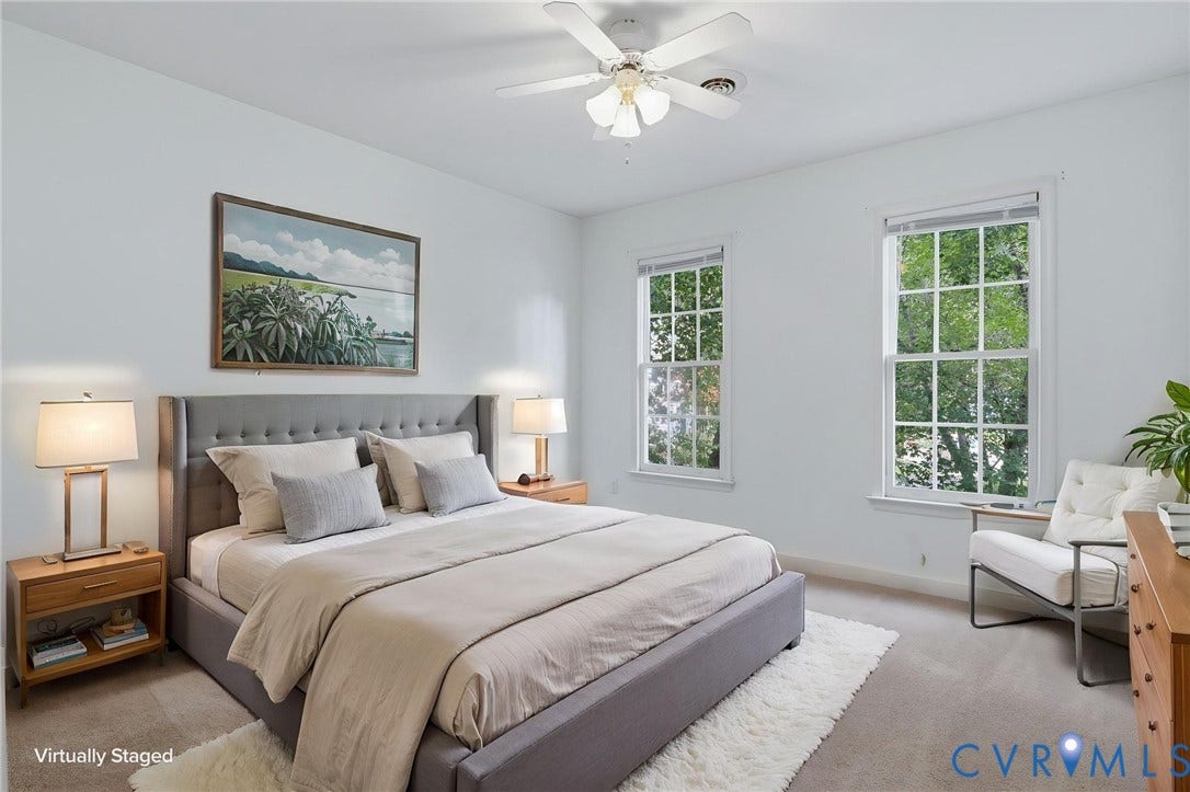 Bright room featuring two tall double-hung windows, a ceiling fan with integrated lighting, and neutral wall paint