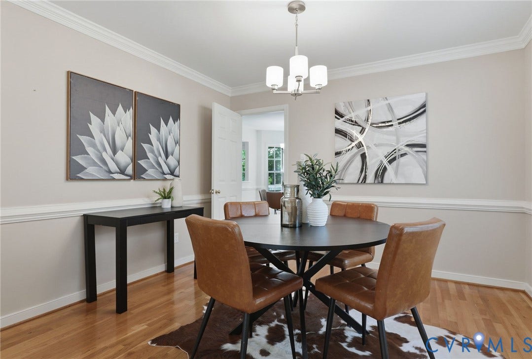 Dining area featuring wood-finish flooring, neutral wall tones, crown molding, and a contemporary chandelier