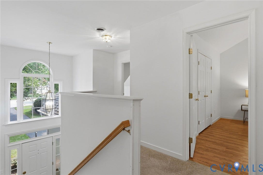 Two-story foyer featuring an arched window, transom windows, and a hanging pendant light fixture