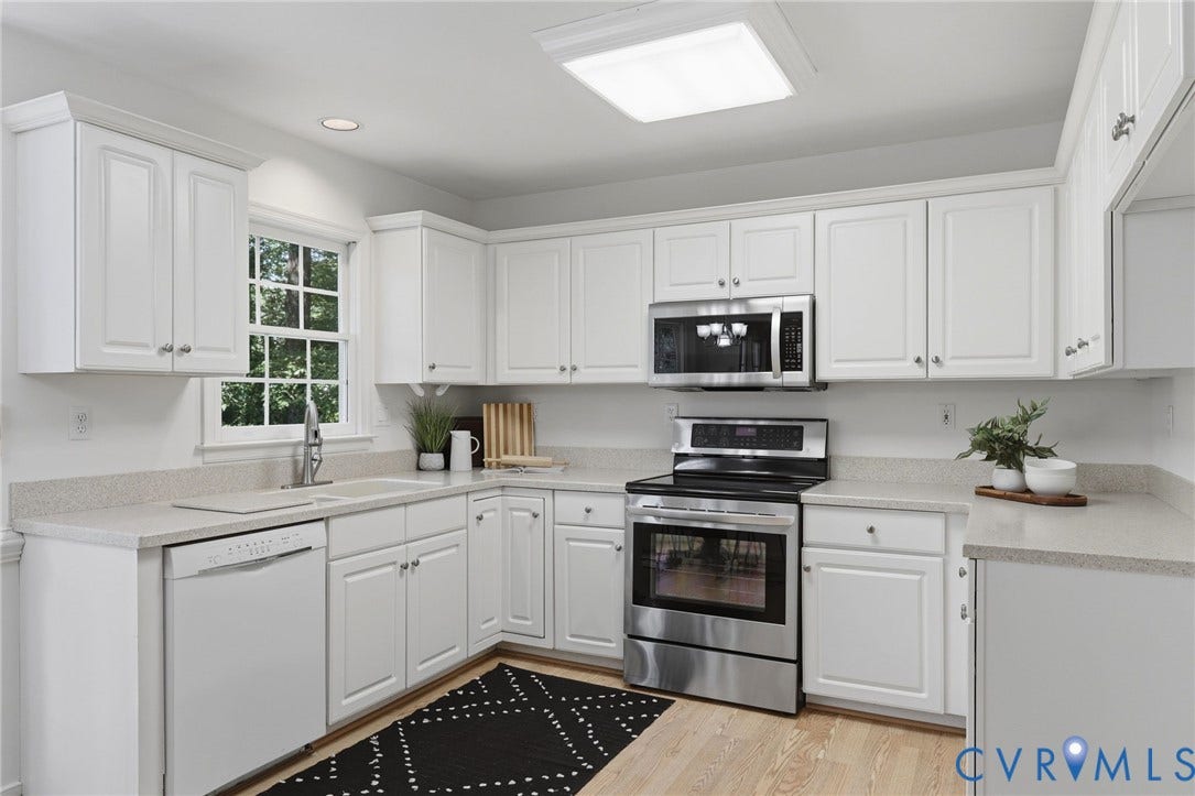 Bright kitchen featuring white cabinetry, Corian countertops, and wood-finish flooring