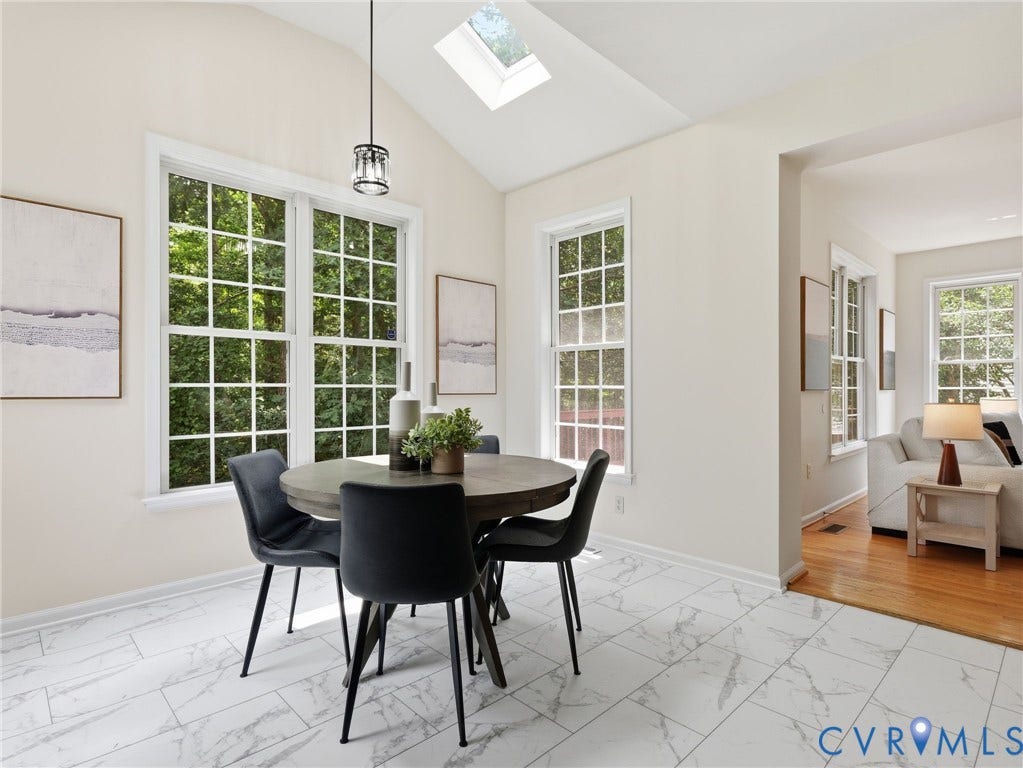 5707 Stephens Point Court, Chesterfield, VA 23831 Dining area featuring a vaulted ceiling with skylight, dual pane windows, a contemporary pendant light fixture, and marble-look tile flooring