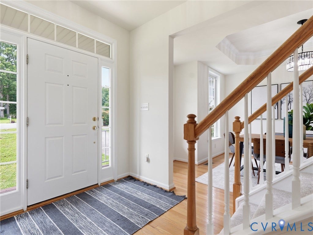 5707 Stephens Point Court, Chesterfield, VA 23831 Front entryway featuring a white paneled door with sidelights and transom window, light wood-finish flooring, and a staircase with wood newel posts and white balusters.