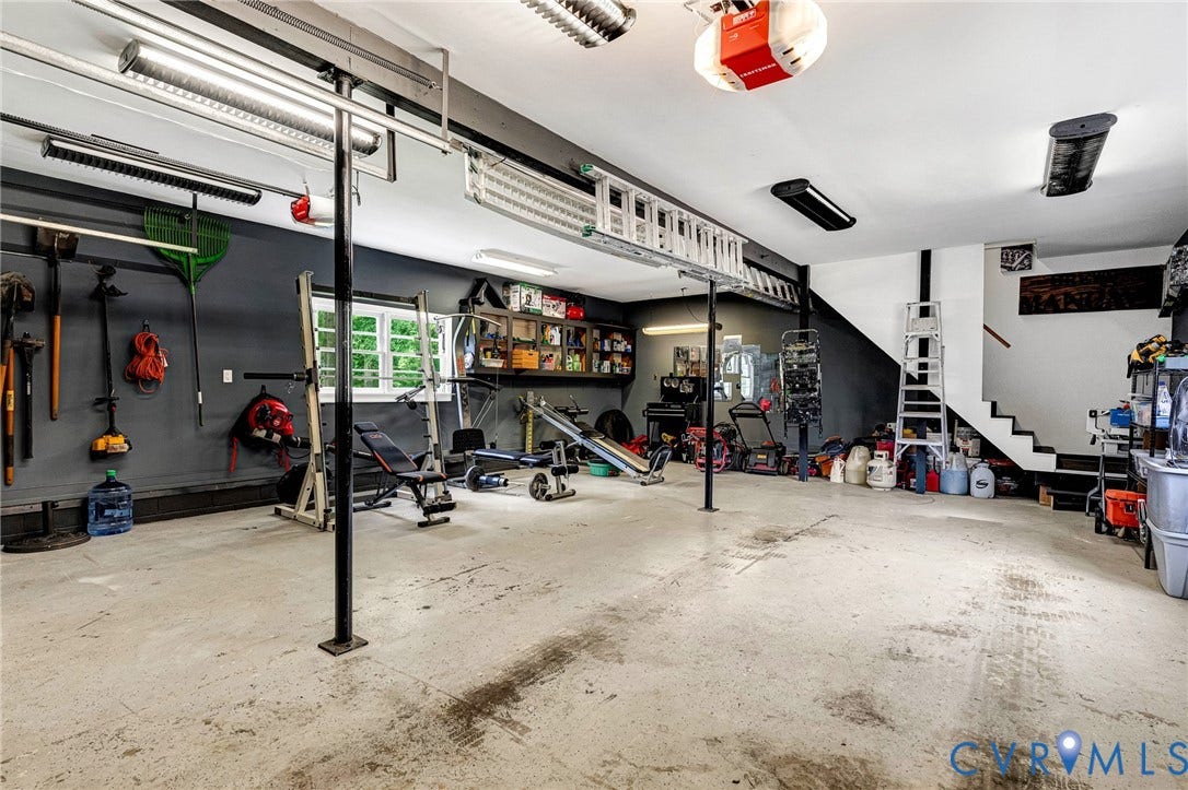 8800 Shewsbury Drive, New Kent, VA 23124 Spacious garage with concrete flooring, overhead fluorescent lighting, and a staircase