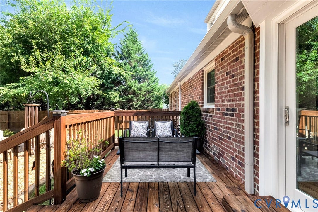 8800 Shewsbury Drive, New Kent, VA 23124 Expansive exterior deck featuring natural wood flooring and railing, brick siding, white gutter system, and a white framed glass door