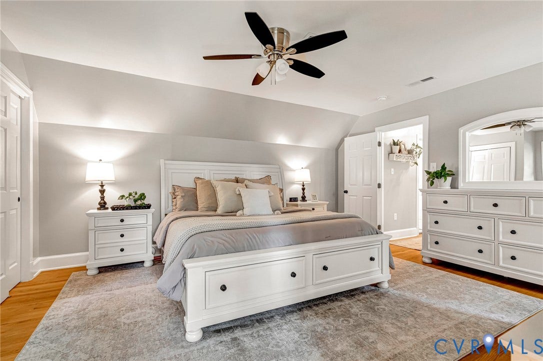 8800 Shewsbury Drive, New Kent, VA 23124 Spacious primary bedroom suite featuring a white painted wood bed frame with storage drawers, dual nightstands with task lighting, and a coordinating dresser with mirror