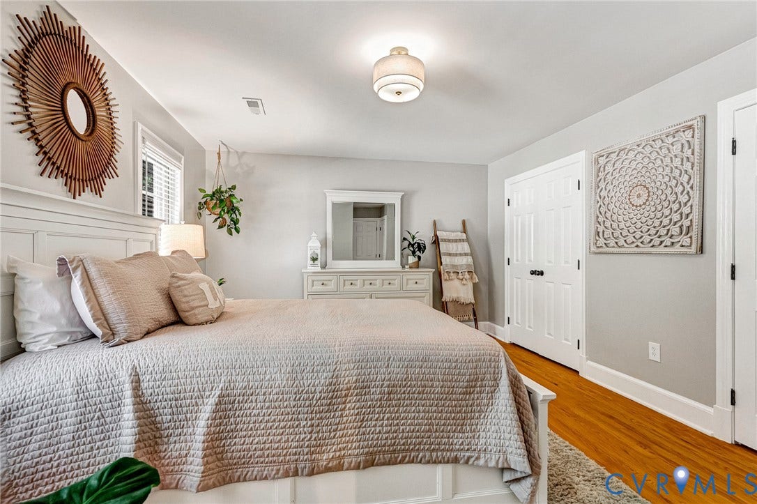 8800 Shewsbury Drive, New Kent, VA 23124 Bedroom featuring wood-finish flooring, white paneled doors with black hardware, and a ceiling-mounted light fixture