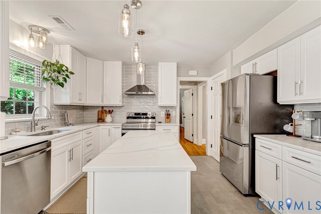 8800 Shewsbury Drive, New Kent, VA 23124 Bright kitchen featuring white shaker cabinetry, stainless steel appliances, a white stone-finish island, and a light gray subway tile backsplash
