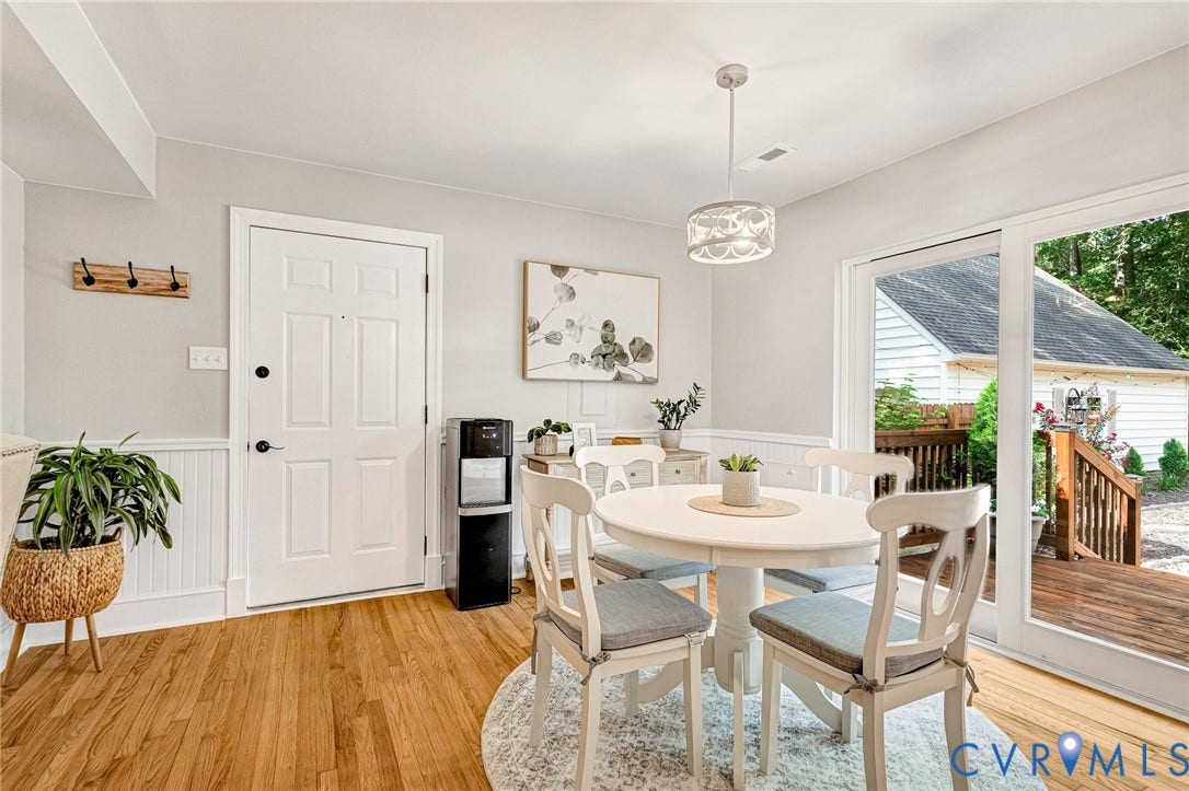 8800 Shewsbury Drive, New Kent, VA 23124 Bright dining area featuring wood-finish flooring, wainscoting, and a sliding glass door providing access to an exterior deck