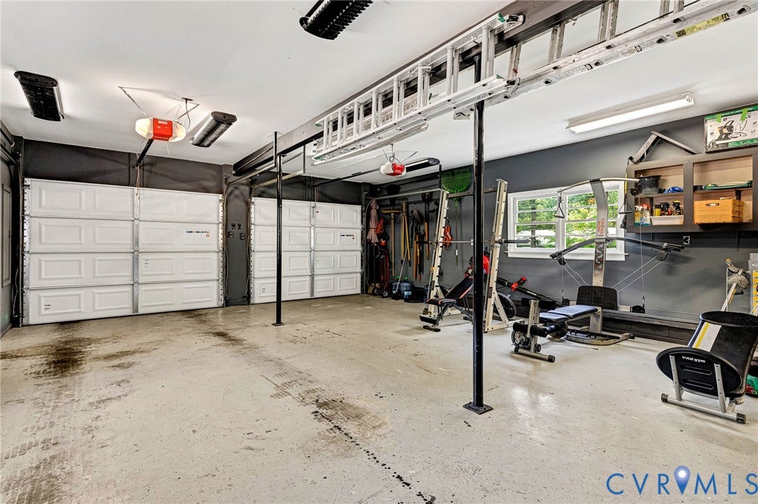 8800 Shewsbury Drive, New Kent, VA 23124 Spacious garage featuring two overhead doors, an epoxy-coated concrete floor, and ample overhead lighting