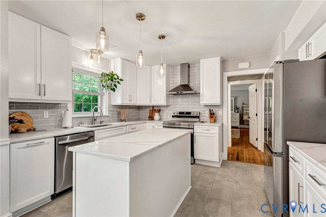 8800 Shewsbury Drive, New Kent, VA 23124 Bright kitchen featuring a central island with a light-toned countertop, white cabinetry with silver hardware, stainless steel appliances, a light-grey subway tile backsplash, and recessed lighting