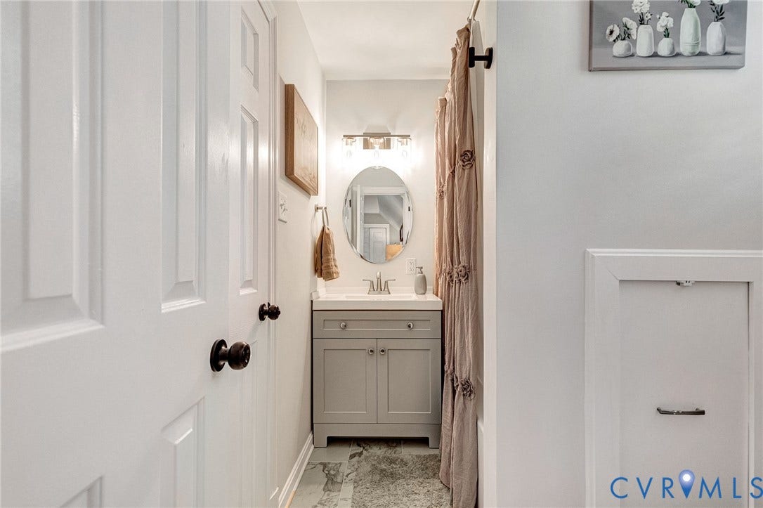 8800 Shewsbury Drive, New Kent, VA 23124 Compact bathroom featuring a single vanity with grey cabinetry, an oval mirror, and overhead lighting