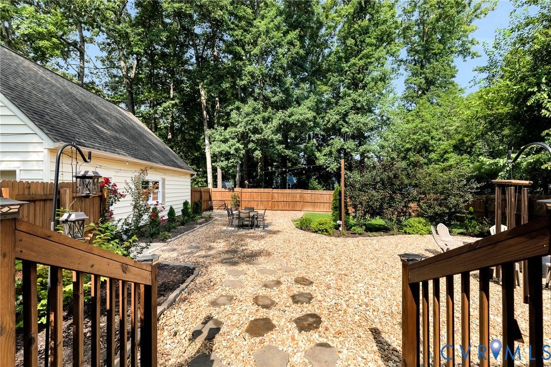 8800 Shewsbury Drive, New Kent, VA 23124 Expansive backyard featuring a gravel patio with stone pavers, a privacy fence, and mature trees