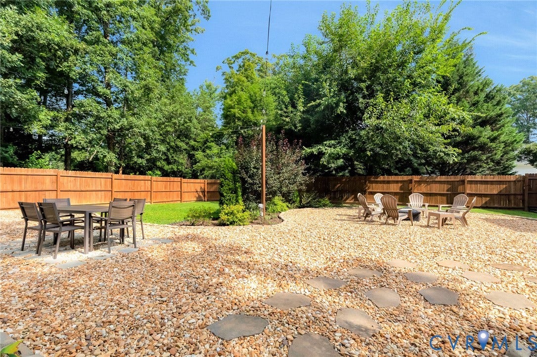 8800 Shewsbury Drive, New Kent, VA 23124 Expansive outdoor space featuring a wood fence, gravel landscaping, stepping stones, and mature perimeter trees