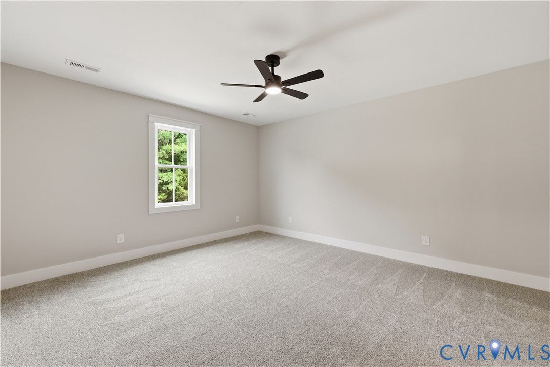 Spacious room featuring neutral carpeting, light gray wall paint, and a single pane window with white trim