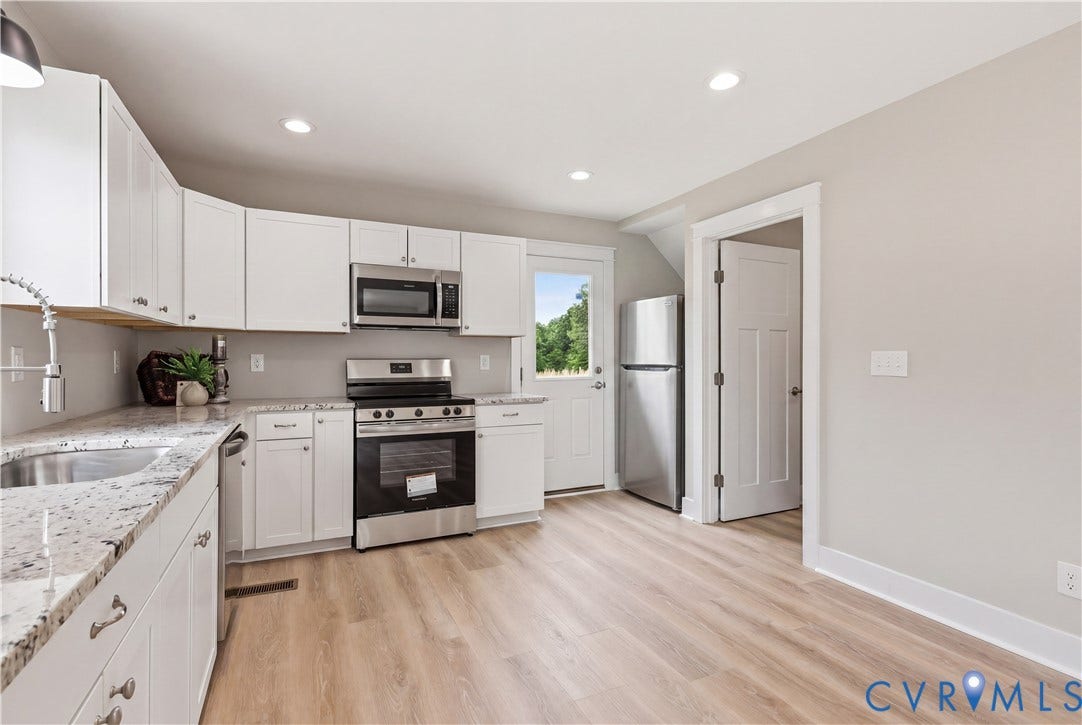 Contemporary kitchen featuring light wood-finish flooring, white cabinetry, speckled countertops, stainless steel appliances, and recessed lighting