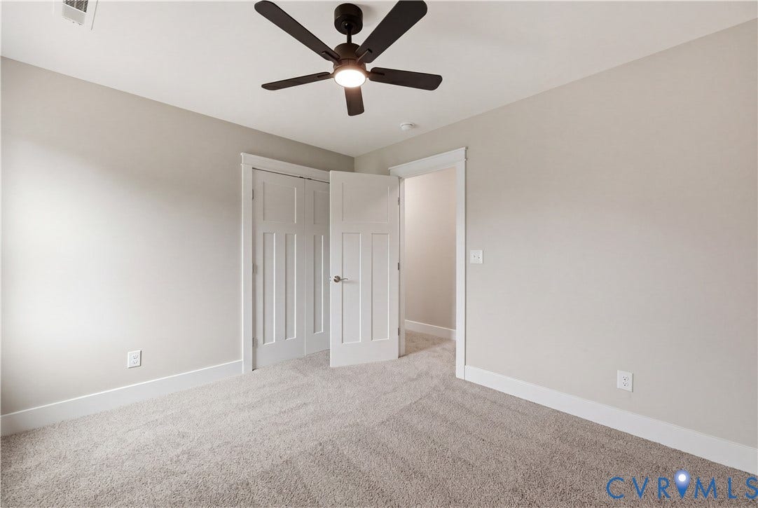 Carpeted room with a ceiling fan light fixture, light gray walls, and white baseboards