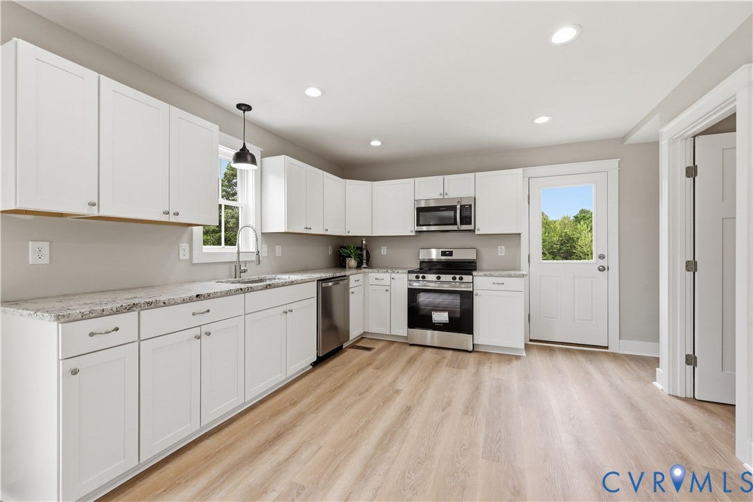 Modern kitchen featuring white shaker cabinetry, light-toned wood-finish flooring, recessed lighting, stainless steel appliances, and light-colored countertops