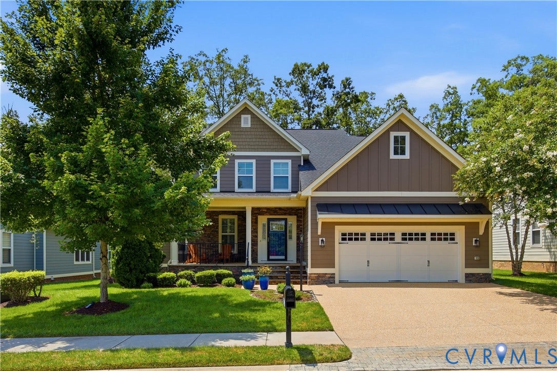 Craftsman-style residence featuring a two-car garage, covered front porch, and a gravel-finish driveway