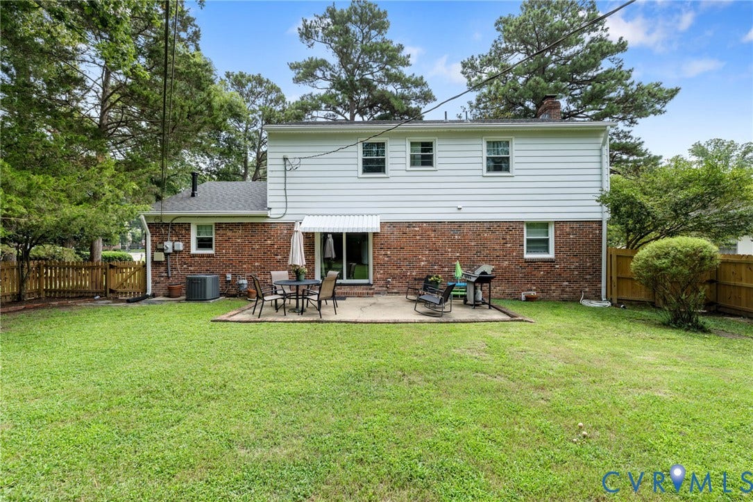 404 Aubery Road, Henrico, VA 23229 Rear exterior featuring a brick and white siding facade, a ground-level patio, and a spacious lawn